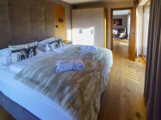 A luxurious bedroom featuring a plush bed with soft blankets and decorative pillows, complemented by a well-lit, modern wardrobe.