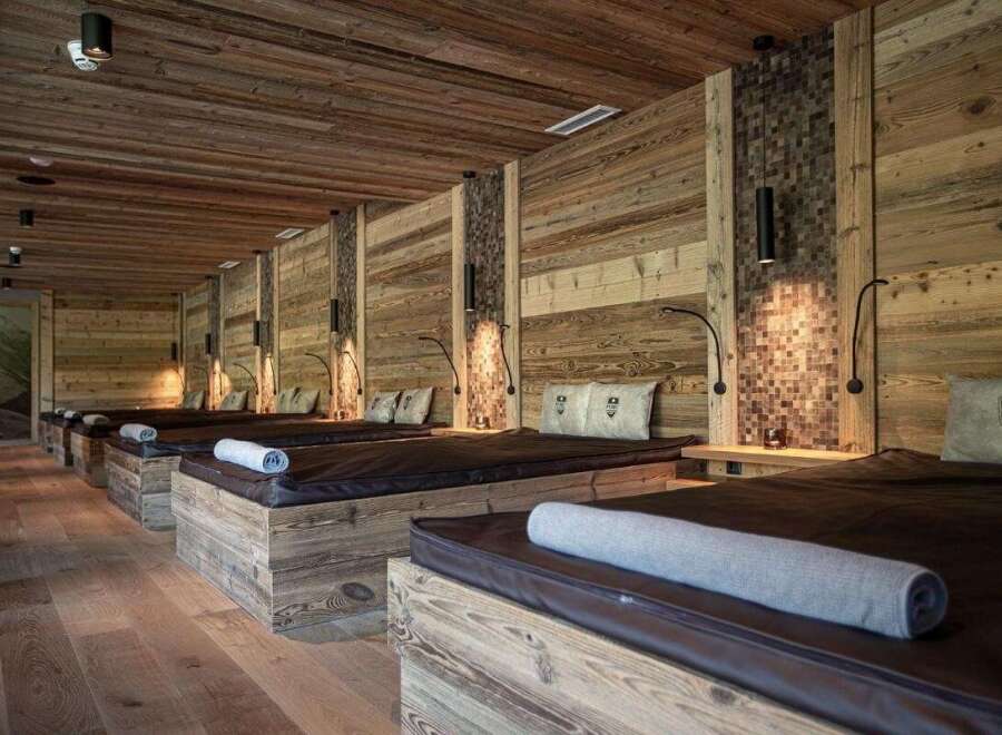 Escape to tranquility in this spa room featuring multiple massage beds with rustic wood frames and warm lighting.