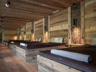 Escape to tranquility in this spa room featuring multiple massage beds with rustic wood frames and warm lighting.