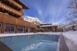 Experience luxury living in this stunning mountain resort, featuring a pristine outdoor pool surrounded by snow-covered landscapes.