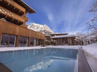 Experience luxury living in this stunning mountain resort, featuring a pristine outdoor pool surrounded by snow-covered landscapes.