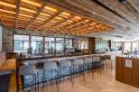 Discover a cozy bar area, designed with a unique stone bar, comfortable stools, and a warm, inviting wooden ceiling with integrated lighting.