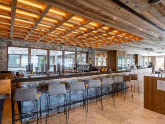 Discover a cozy bar area, designed with a unique stone bar, comfortable stools, and a warm, inviting wooden ceiling with integrated lighting.