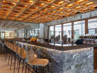 This stylish bar area features a unique wooden grid ceiling with warm lighting, complemented by marble countertops and stone walls.
