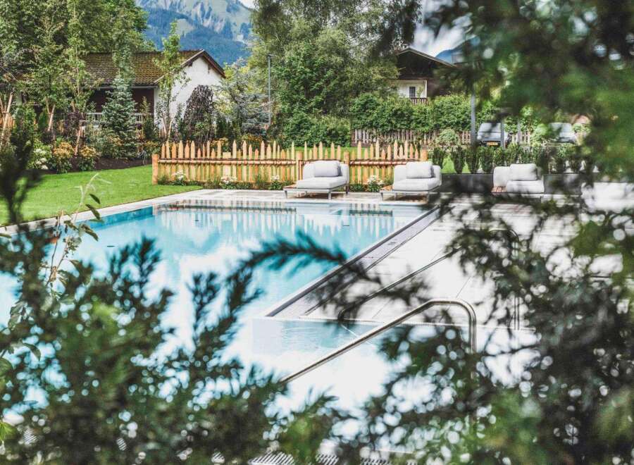 Escape to this stunning property featuring a pristine pool surrounded by lush greenery and charming wooden accents.