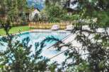 Escape to this stunning property featuring a pristine pool surrounded by lush greenery and charming wooden accents.