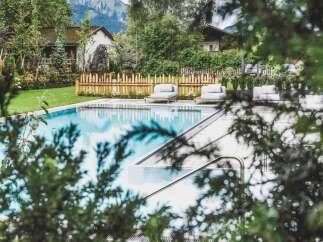 Escape to this stunning property featuring a pristine pool surrounded by lush greenery and charming wooden accents.