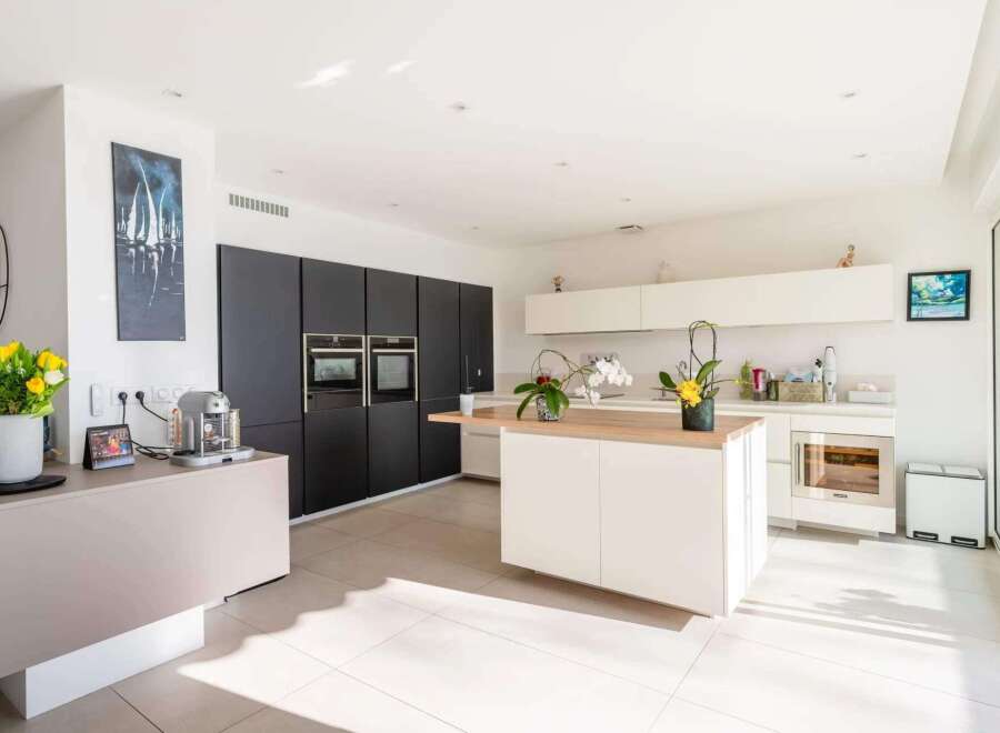 This stunning modern kitchen boasts sleek dark cabinetry, high-end appliances, and a spacious island with a light wood countertop.
