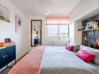 Stylish bedroom with a comfortable king-size bed, built-in shelving, and large window offering scenic views.