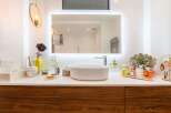 This stunning bathroom boasts a modern design with walnut cabinetry and a sleek white sink.
