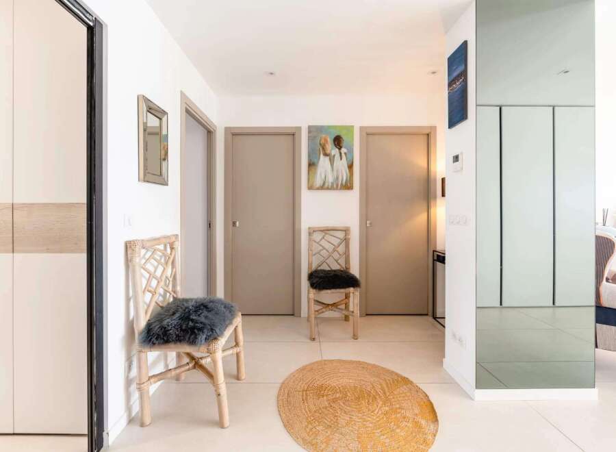 Bright and airy hallway with stylish decor, featuring two comfortable chairs and a jute rug.
