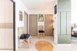 Bright and airy hallway with stylish decor, featuring two comfortable chairs and a jute rug.