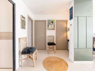 Bright and airy hallway with stylish decor, featuring two comfortable chairs and a jute rug.