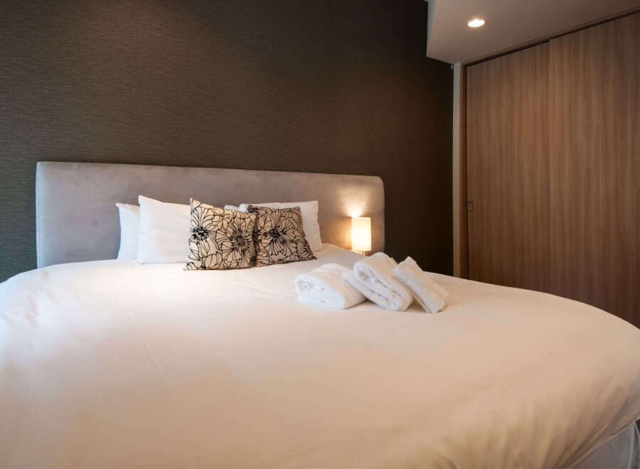 Relax in this cozy bedroom featuring a comfortable double bed, plush pillows, and neatly folded towels.