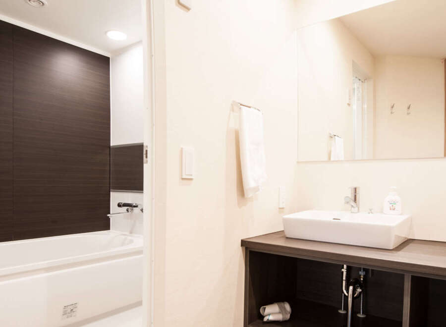This modern bathroom boasts a sleek, dark-wood paneled bathtub and a contemporary vanity with a clean white sink.