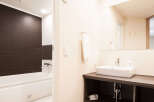This modern bathroom boasts a sleek, dark-wood paneled bathtub and a contemporary vanity with a clean white sink.