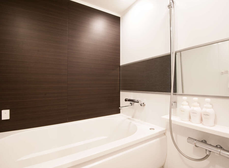 This modern bathroom boasts a sleek, white bathtub and dark brown wood-paneled walls, creating a stylish and relaxing atmosphere.