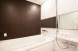 This modern bathroom boasts a sleek, white bathtub and dark brown wood-paneled walls, creating a stylish and relaxing atmosphere.