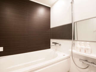 This modern bathroom boasts a sleek, white bathtub and dark brown wood-paneled walls, creating a stylish and relaxing atmosphere.