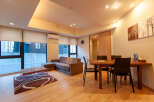 This modern apartment boasts an open-plan living area with hardwood floors, large windows offering ample natural light, and a comfortable sofa set.