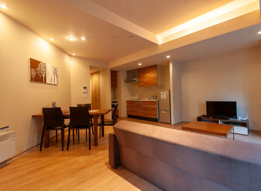 This modern apartment boasts an open-plan living area with a comfortable sofa, a dining table for four, and a fully equipped kitchen.