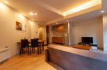 This modern apartment boasts an open-plan living area with a comfortable sofa, a dining table for four, and a fully equipped kitchen.