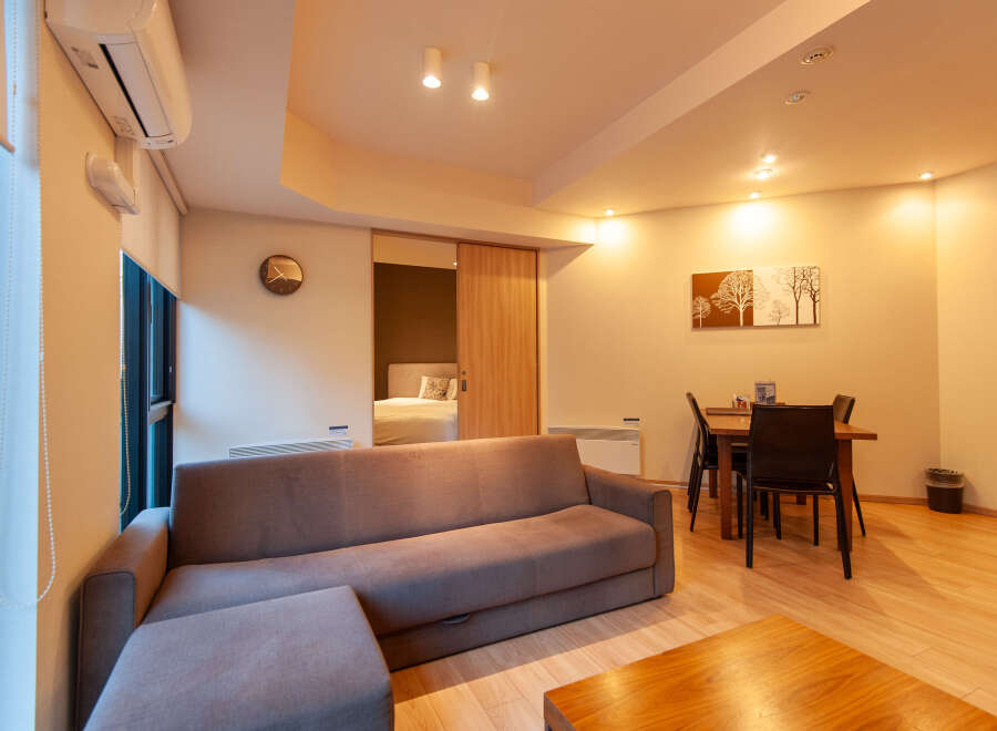 This modern apartment boasts an open-plan living area with a comfortable sofa and ottoman, perfect for relaxing.