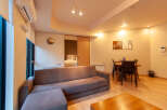 This modern apartment boasts an open-plan living area with a comfortable sofa and ottoman, perfect for relaxing.