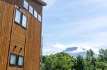 This stunning property boasts a modern design with a rustic wooden exterior, complemented by large windows offering breathtaking views of the surrounding landscape.