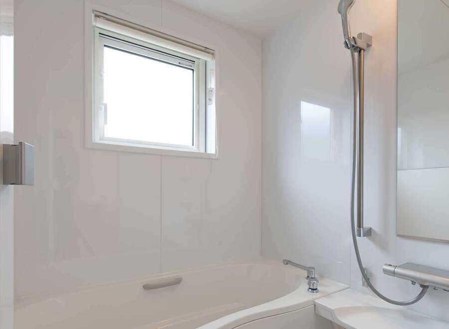 This modern bathroom boasts a sleek, white design with a built-in bathtub and shower combination.