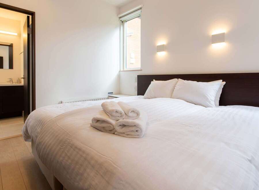 This cozy bedroom features a comfortable double bed with crisp white linens and fluffy towels, perfect for a relaxing stay.