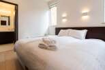This cozy bedroom features a comfortable double bed with crisp white linens and fluffy towels, perfect for a relaxing stay.