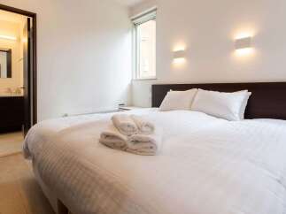 This cozy bedroom features a comfortable double bed with crisp white linens and fluffy towels, perfect for a relaxing stay.