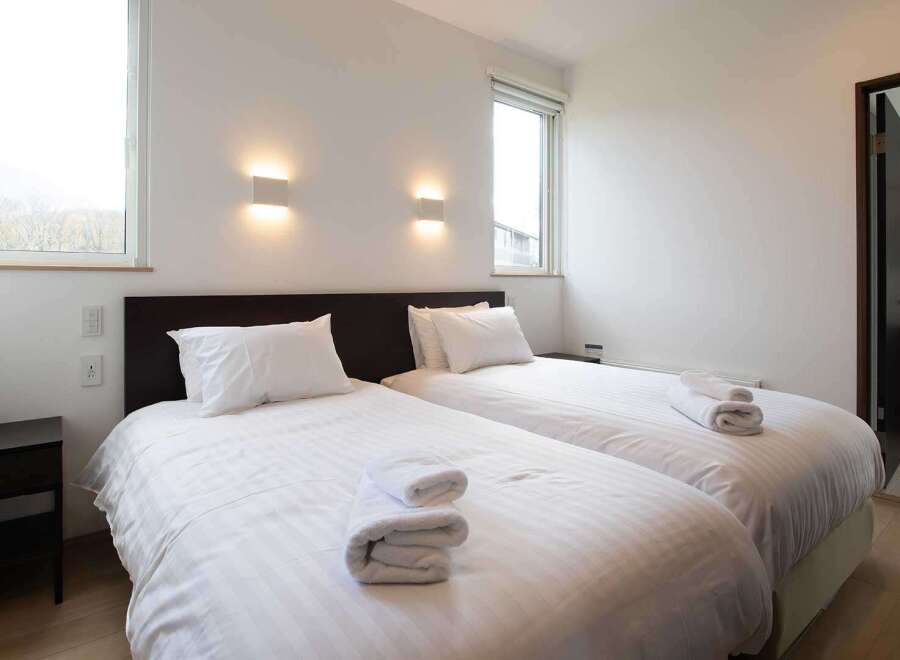 This cozy bedroom features two twin beds with crisp white linens, perfect for a relaxing stay.