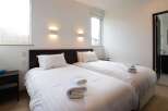 This cozy bedroom features two twin beds with crisp white linens, perfect for a relaxing stay.