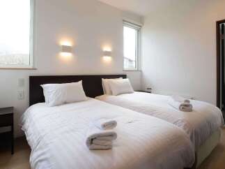 This cozy bedroom features two twin beds with crisp white linens, perfect for a relaxing stay.