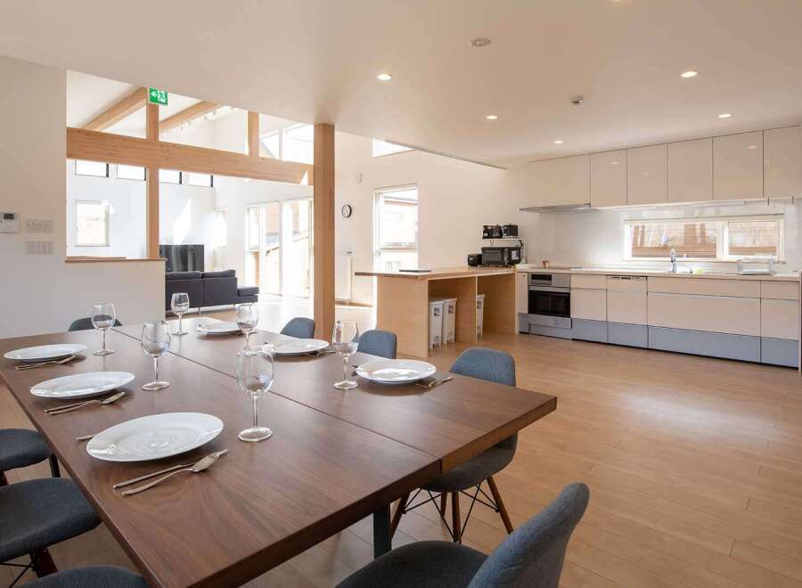 This stunning property boasts a spacious open-plan living area with a large dining table perfect for entertaining, seamlessly flowing into a modern, well-equipped kitchen.