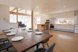 This stunning property boasts a spacious open-plan living area with a large dining table perfect for entertaining, seamlessly flowing into a modern, well-equipped kitchen.
