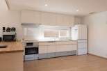 This modern kitchen boasts sleek white cabinetry, integrated appliances, and a light wood countertop.