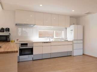 This modern kitchen boasts sleek white cabinetry, integrated appliances, and a light wood countertop.
