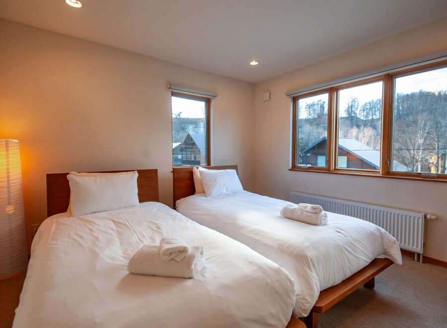 This cozy bedroom features two twin beds with crisp white linens and fluffy towels, perfect for a relaxing stay.