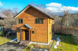 This charming two-story house boasts a warm wood exterior, perfect for a cozy mountain getaway.