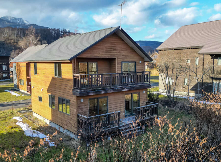 This charming two-story wooden house boasts a spacious balcony and deck, perfect for enjoying mountain views.