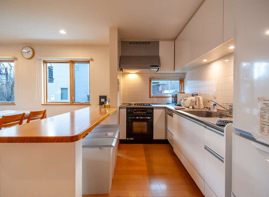 This modern kitchen boasts a sleek design with white cabinetry, wood countertops, and stainless steel appliances.