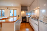 This modern kitchen boasts a sleek design with white cabinetry, wood countertops, and stainless steel appliances.