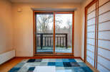 This serene room features a sliding glass door that opens to a deck overlooking a tranquil wooded area, offering a peaceful view.