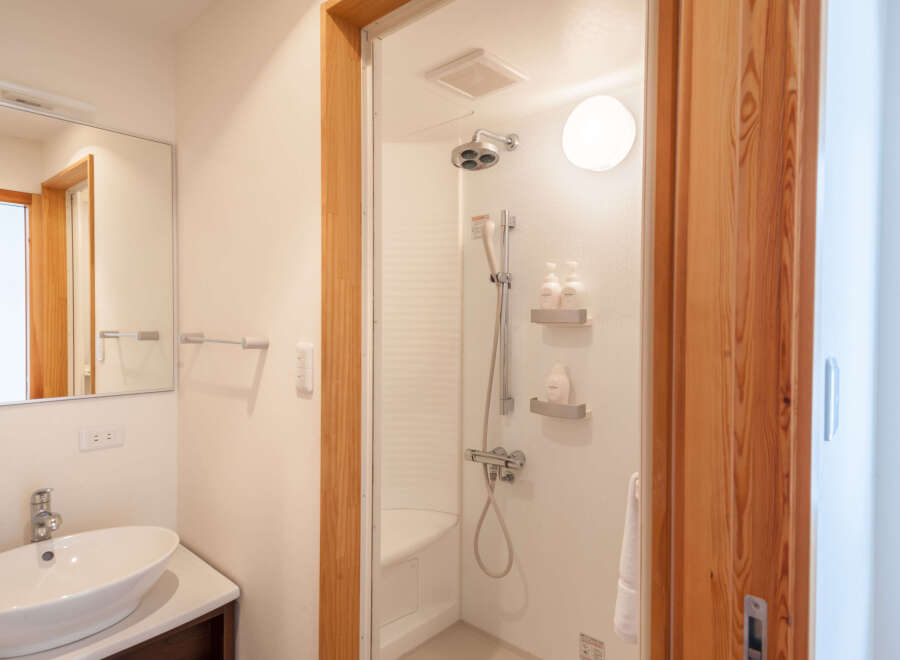 This modern bathroom boasts a sleek, white shower stall with built-in shelving for toiletries and a comfortable seat.