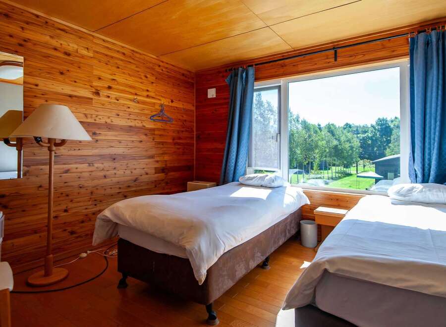 This cozy wooden room features two single beds, perfect for a relaxing getaway.