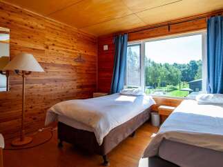 This cozy wooden room features two single beds, perfect for a relaxing getaway.
