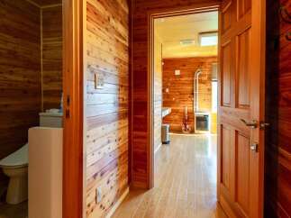 This charming wooden cabin boasts a cozy interior with knotty pine walls and hardwood floors throughout.